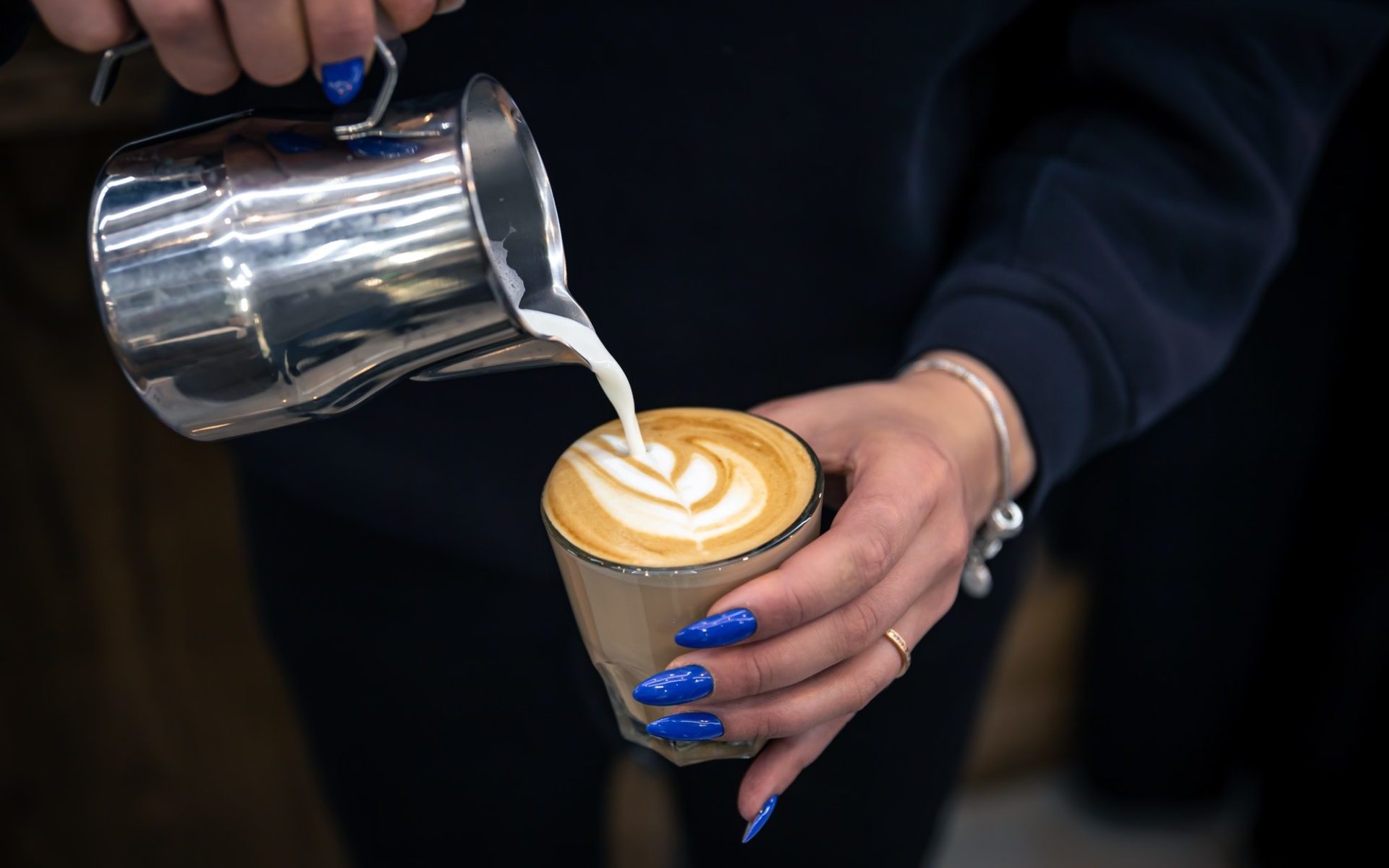 close-up-hand-of-a-woman-barista-pouring-froth-milk-in-espresso-coffee--e1651630473618